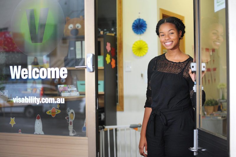 A woman smiling and opening a door