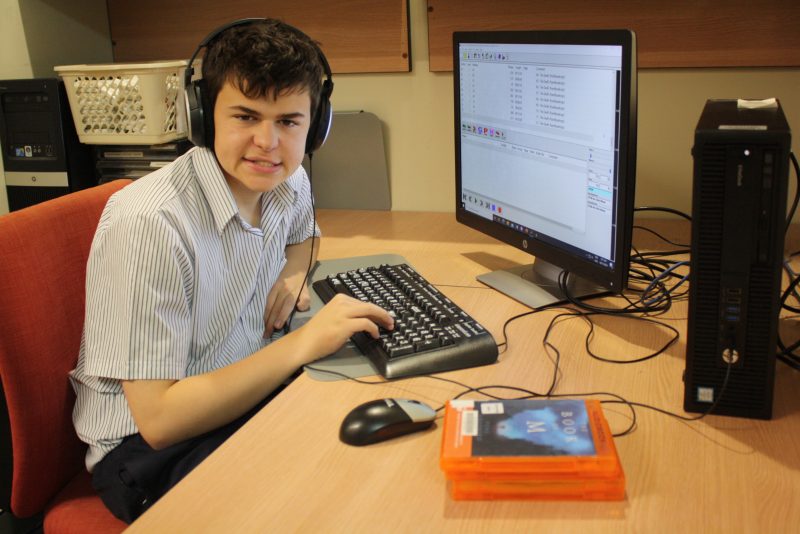 A teenage boy working on he computer creating audio books.