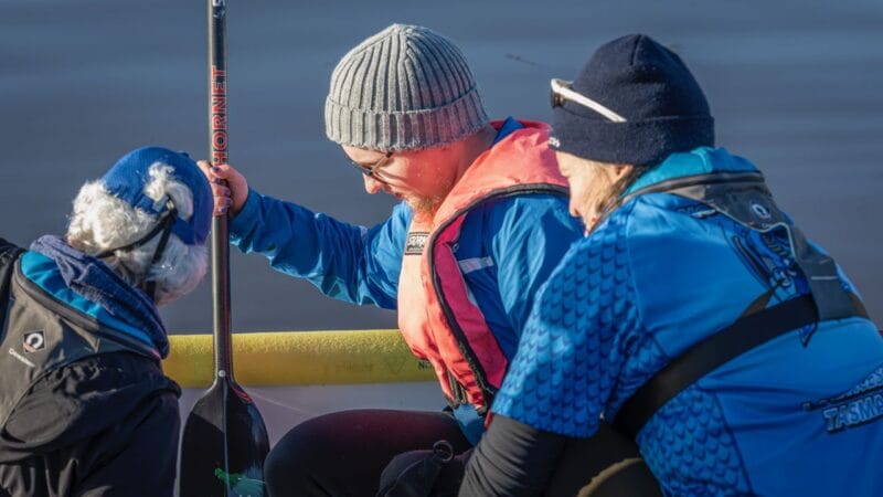 Elliot being supported to safely settle into position on the dragon boat